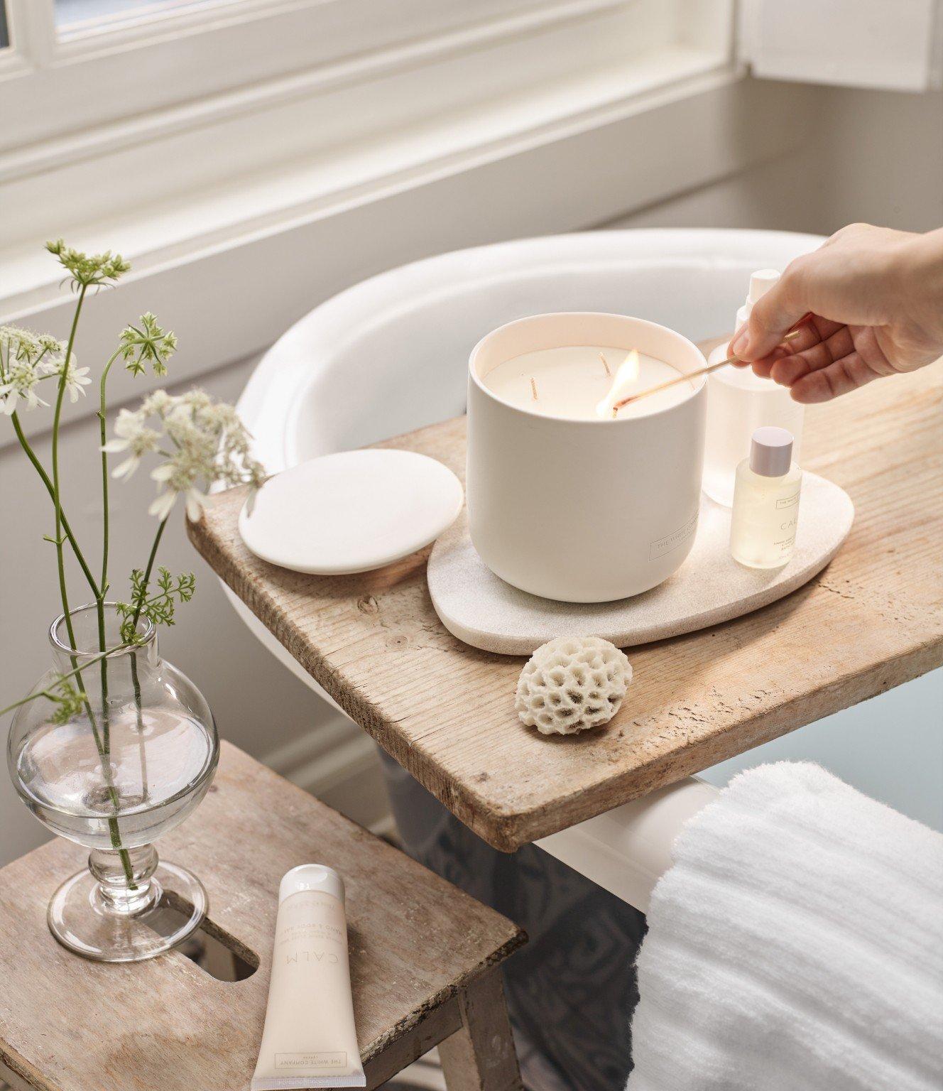 a person is holding a candle in a bathtub with a wooden tray