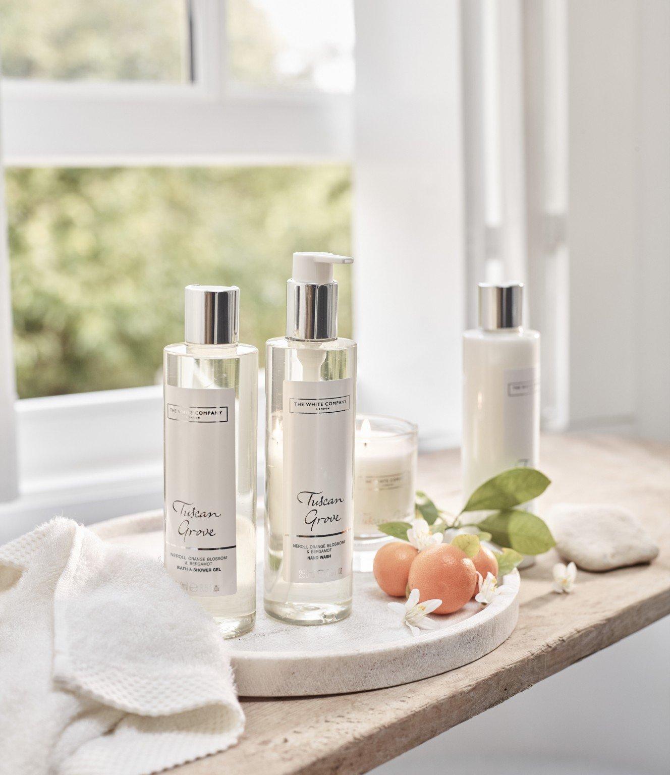 a tray with three bottles of lotion and a small bowl of fruit