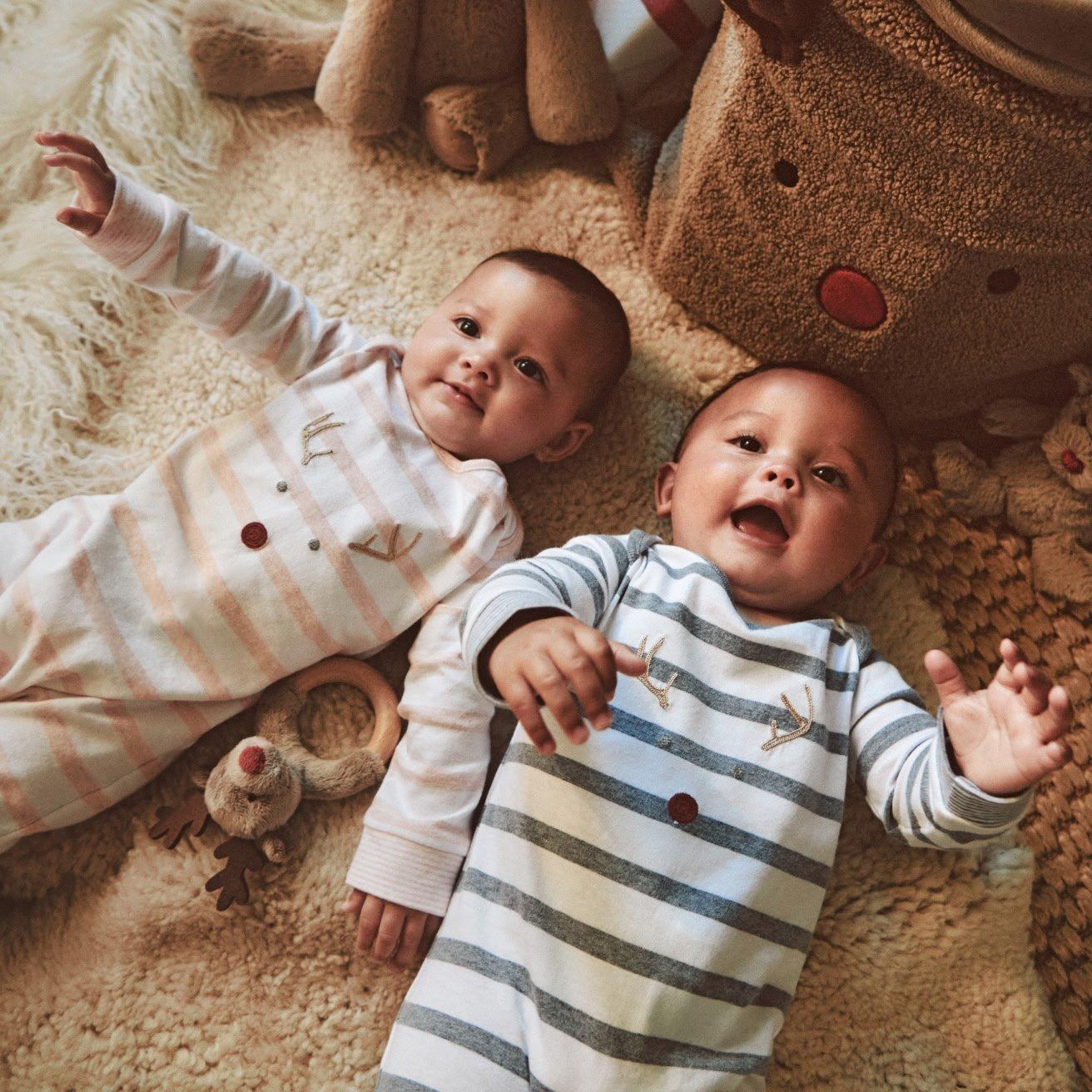 a baby sitting on a bed with a stuffed animal