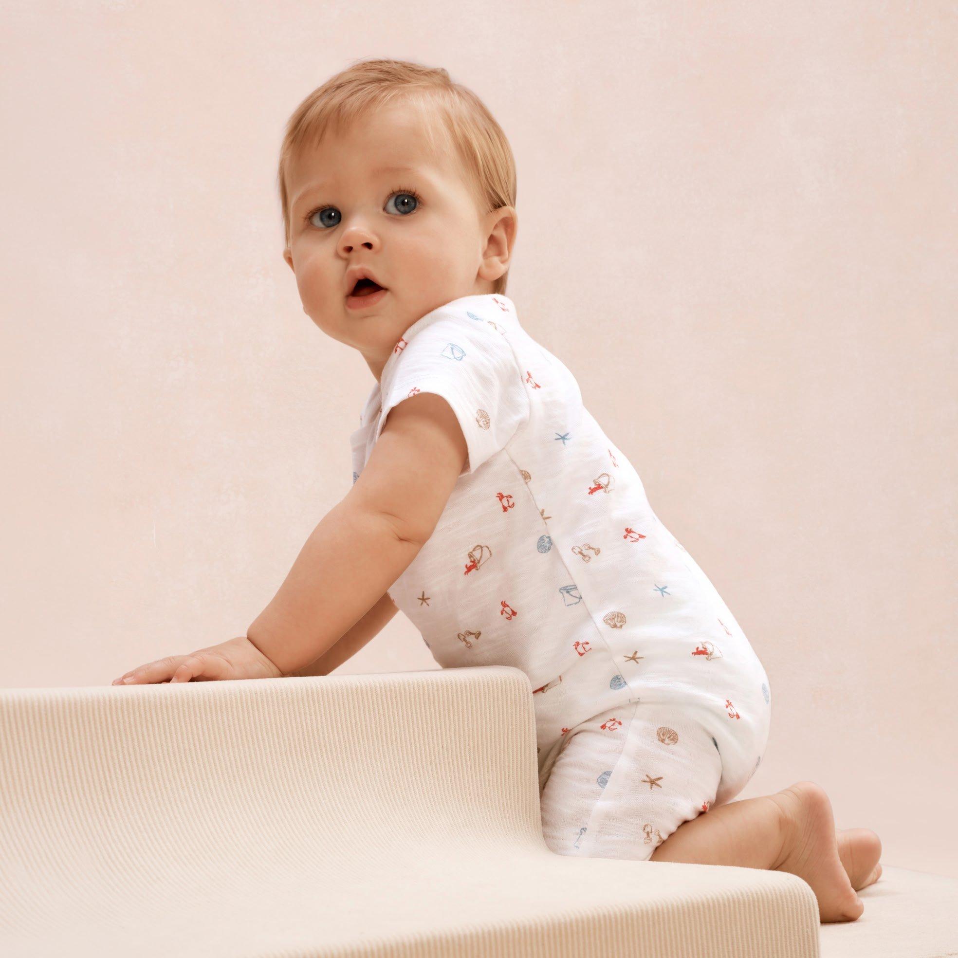 a baby crawling up a stairway in a white outfit
