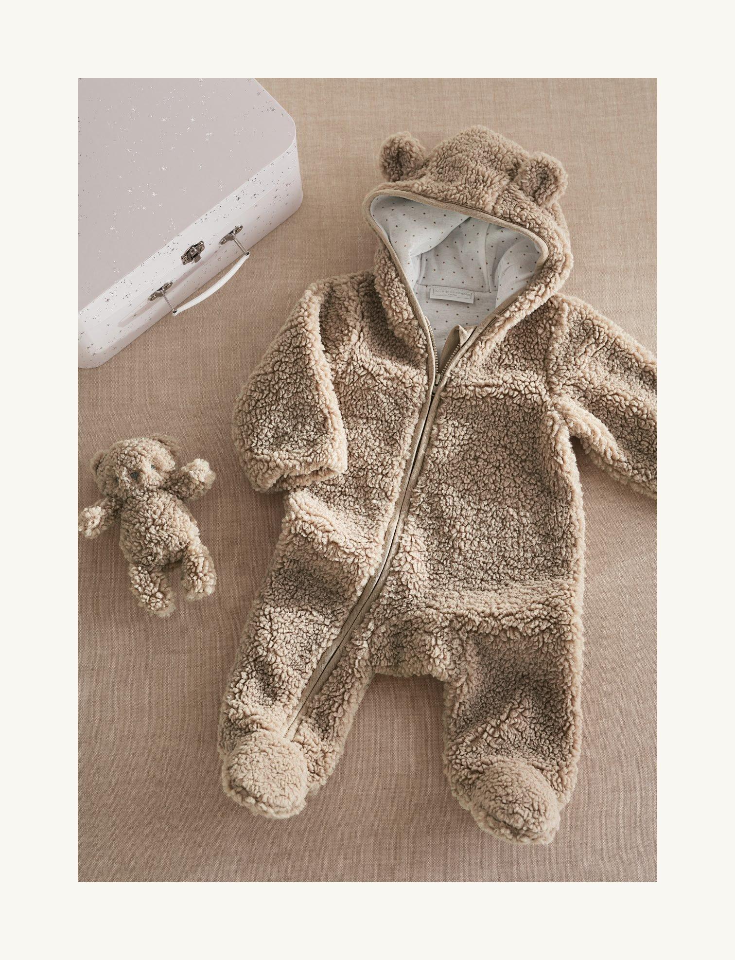 a white baby outfit with a white rabbit sitting next to it