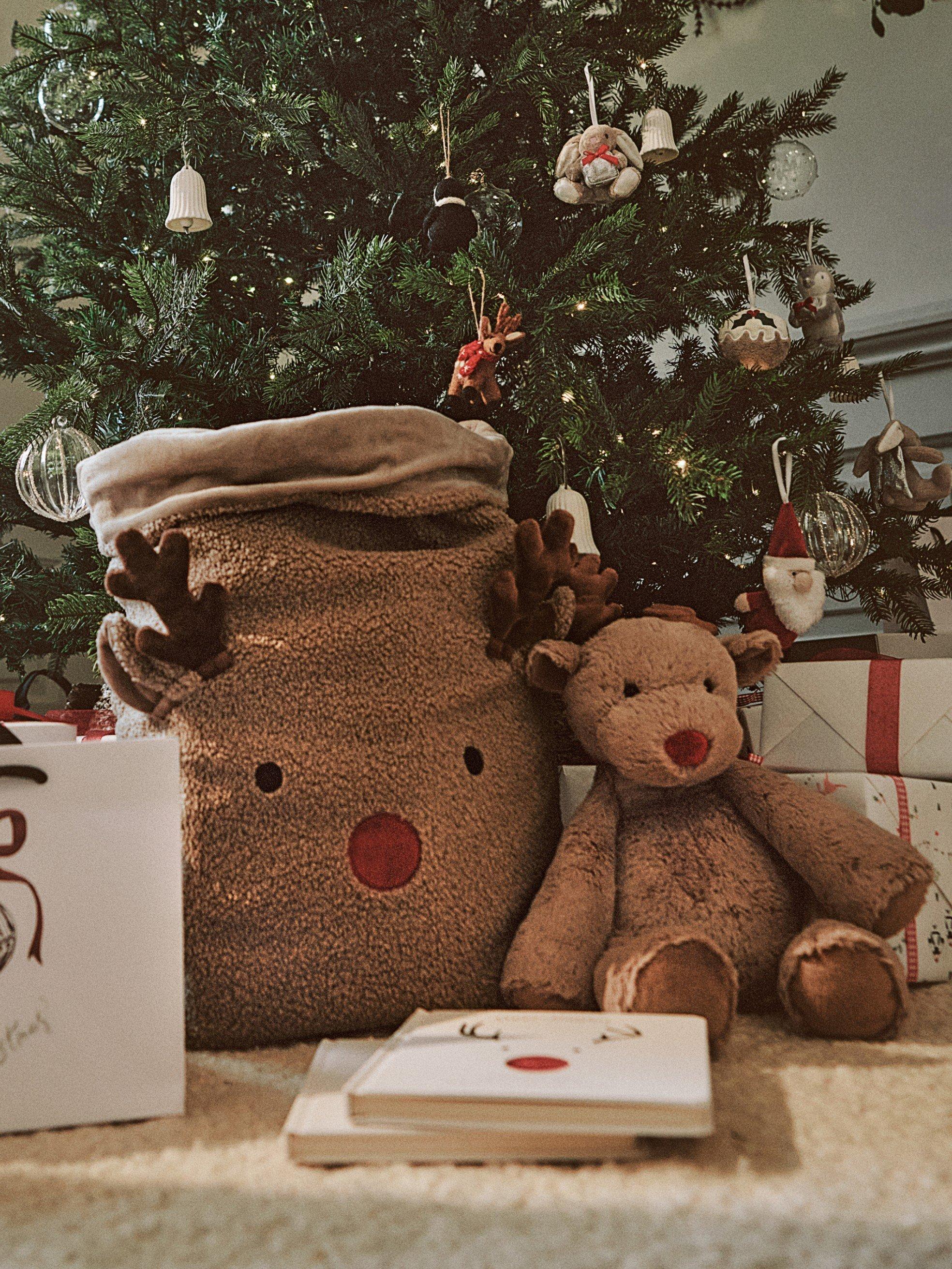 a stuffed animal sitting next to a christmas tree with presents
