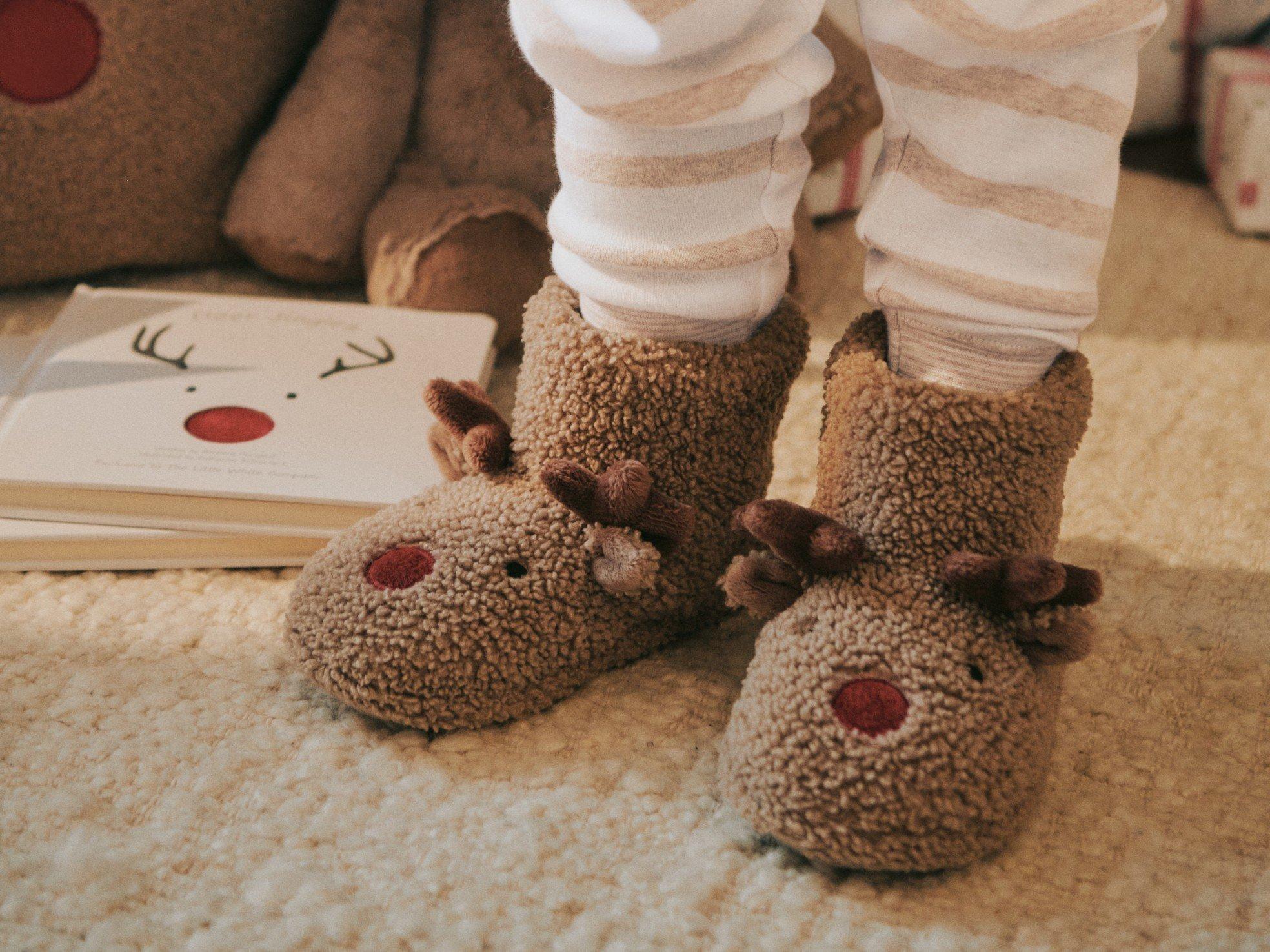 a child's feet in a pair of slippers with reindeer antlers