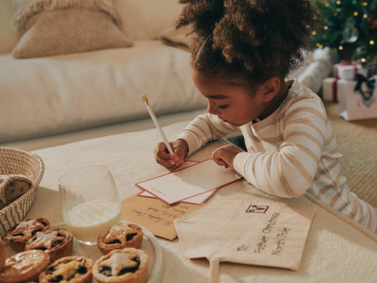 a little girl writing a letter to her family on christmas morning
