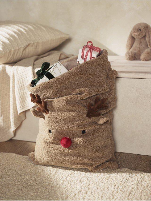 a bag with a stuffed reindeer on it sitting on a bed