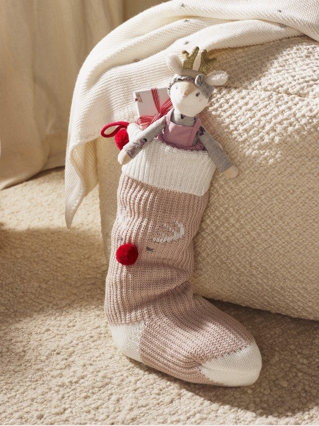 a stuffed toy is sitting in a sock on a bed