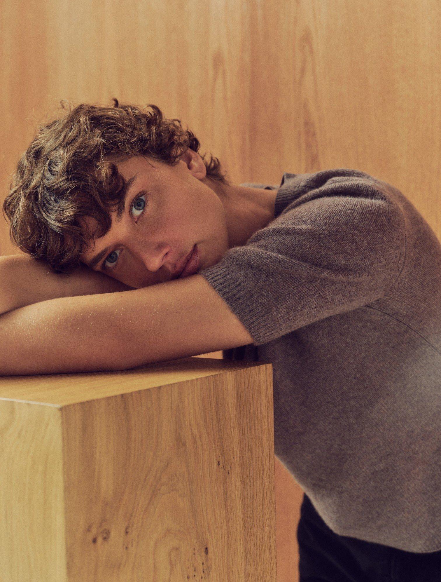 a young man leaning on a wooden box with his head down