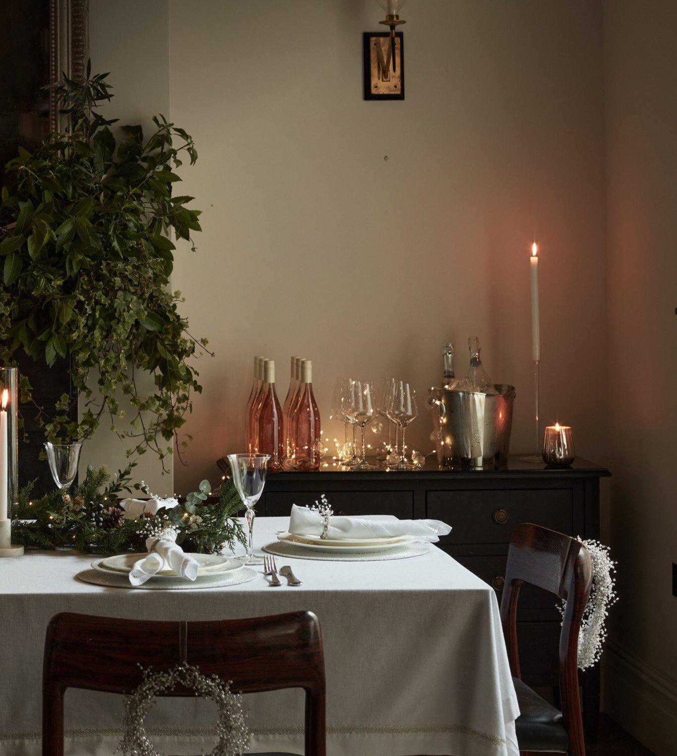 a dining room with a table set for a meal with candles and wine