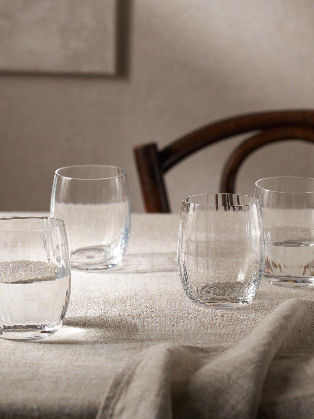 a table with four glasses of water on it and a chair