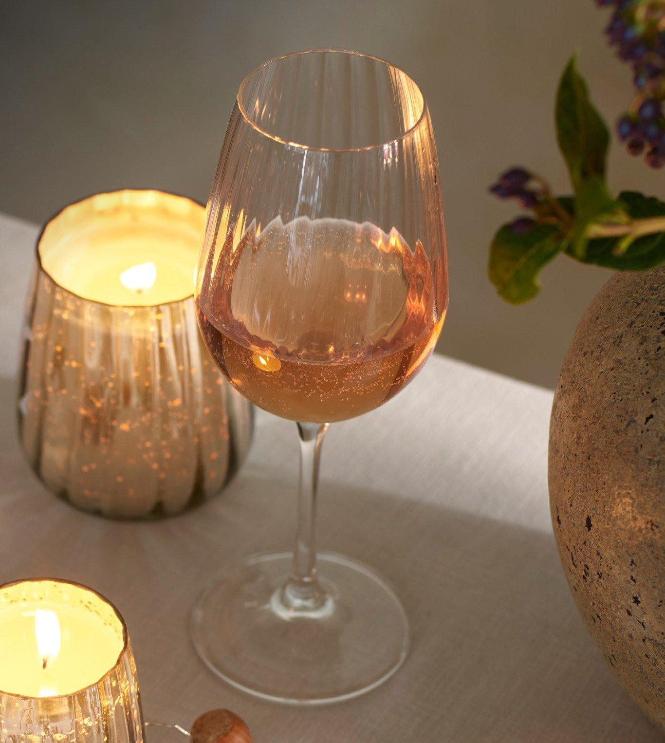 a glass of wine on a table with candles and other items