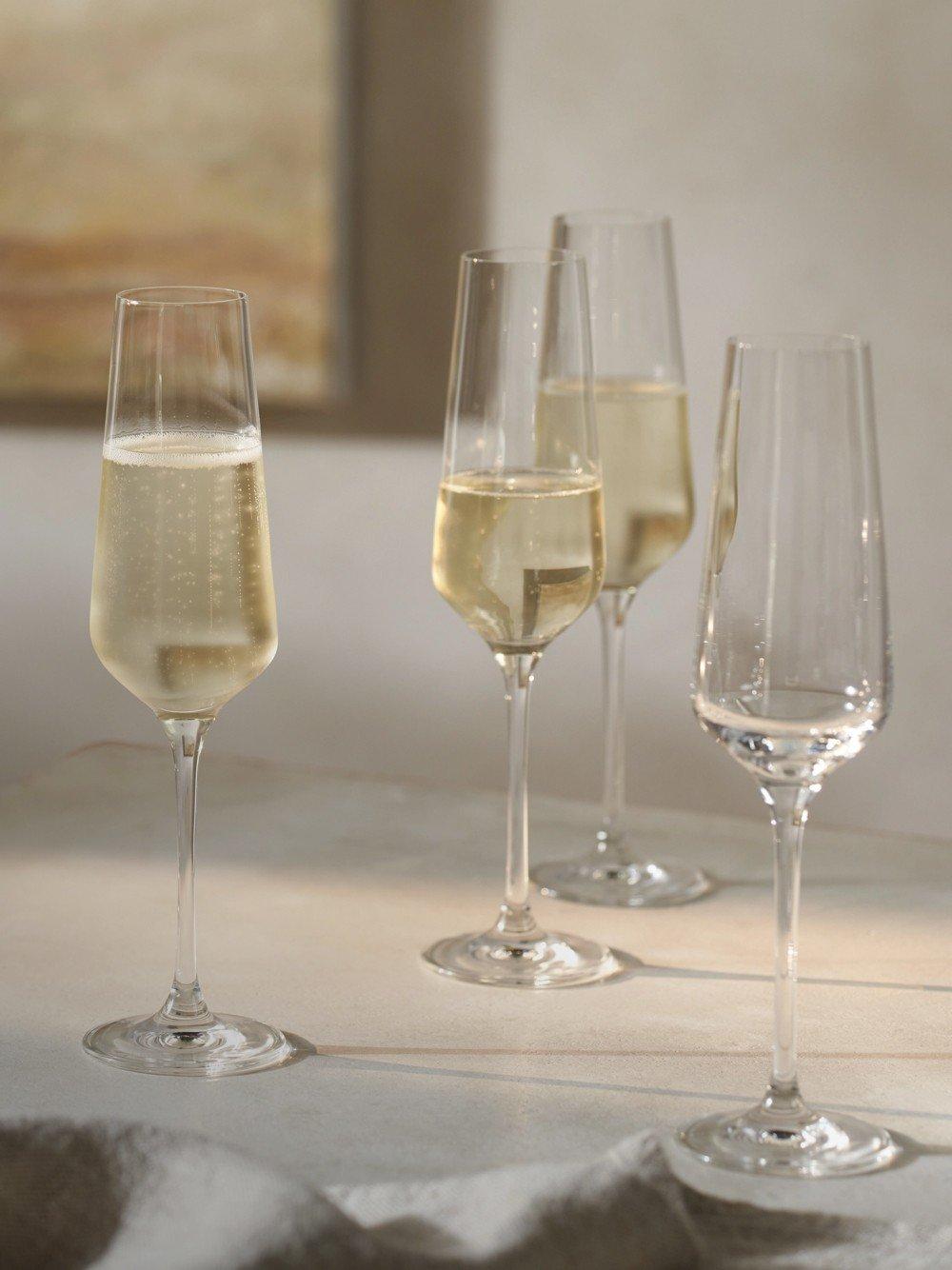 a group of three wine glasses on a table with a painting