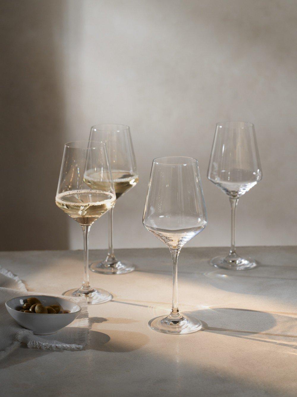 a group of wine glasses on a table with a bowl of olives