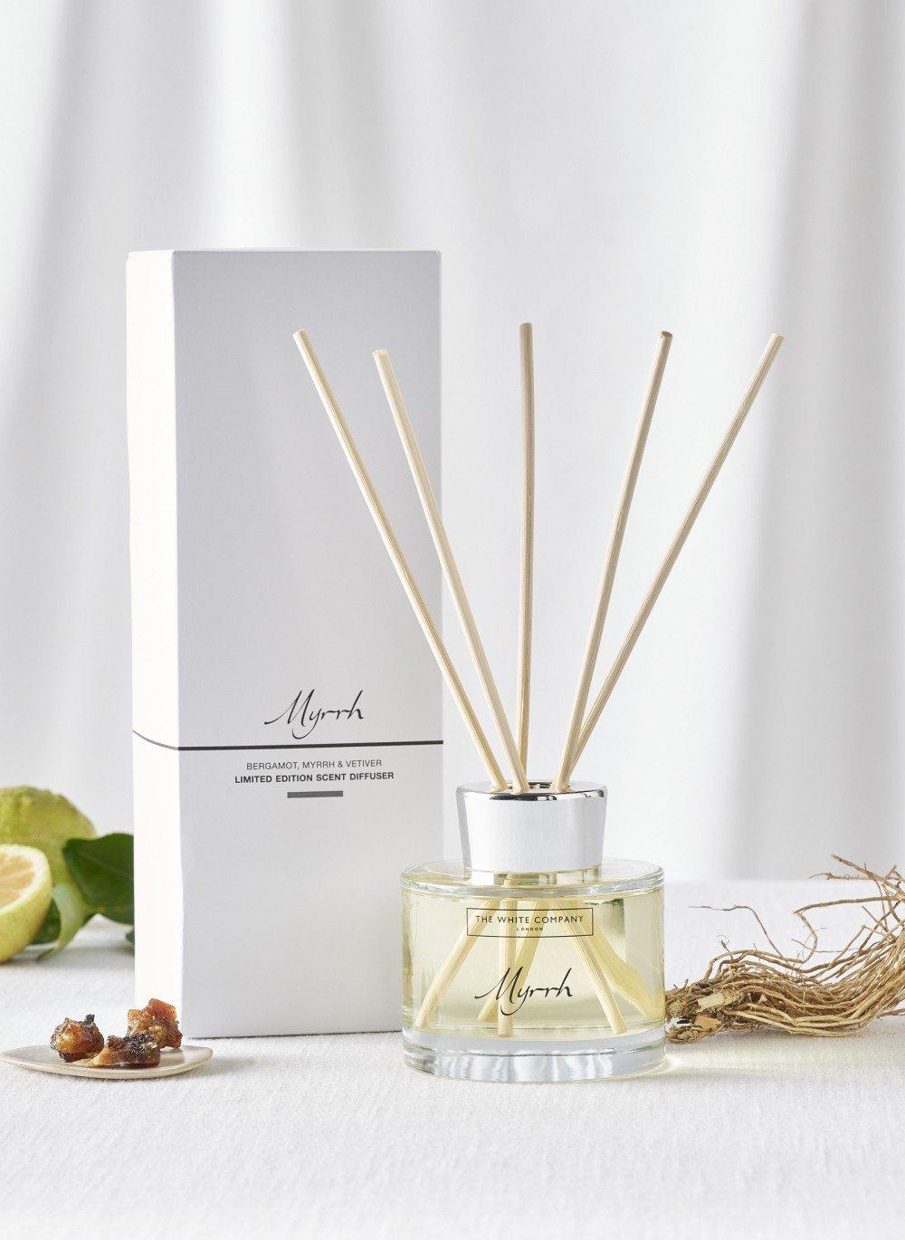 a reed diffuser with a box and some limes next to it