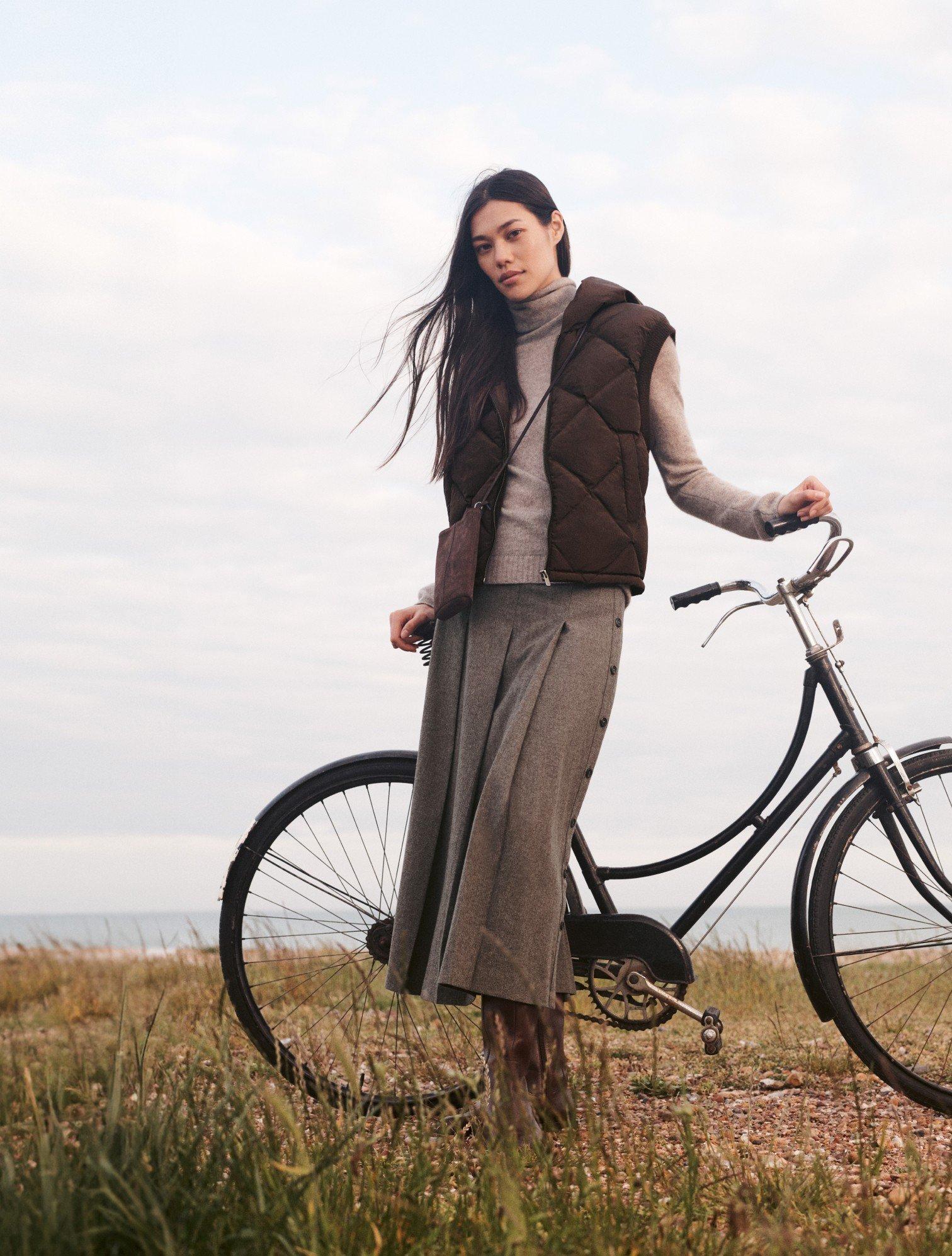 a woman standing next to a bike in a field