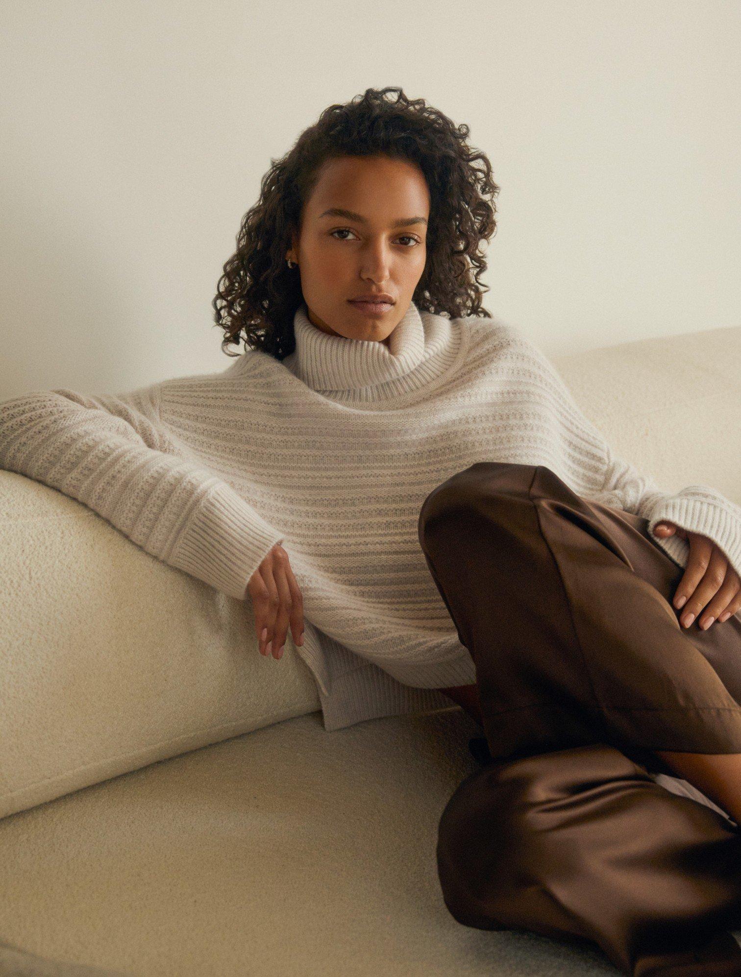 a woman in a white sweater sitting on a couch