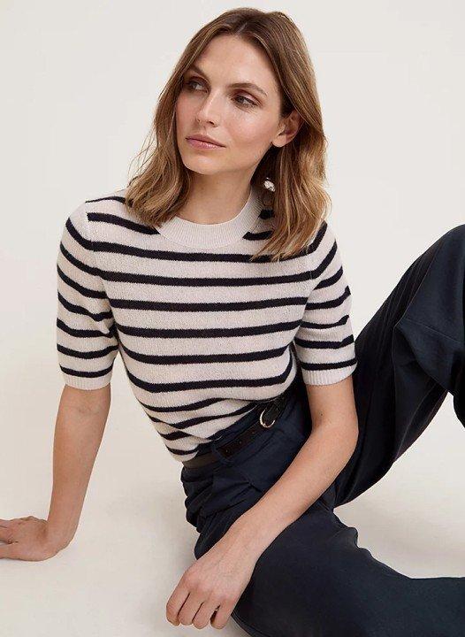 a woman in a striped shirt and pants sitting on the floor