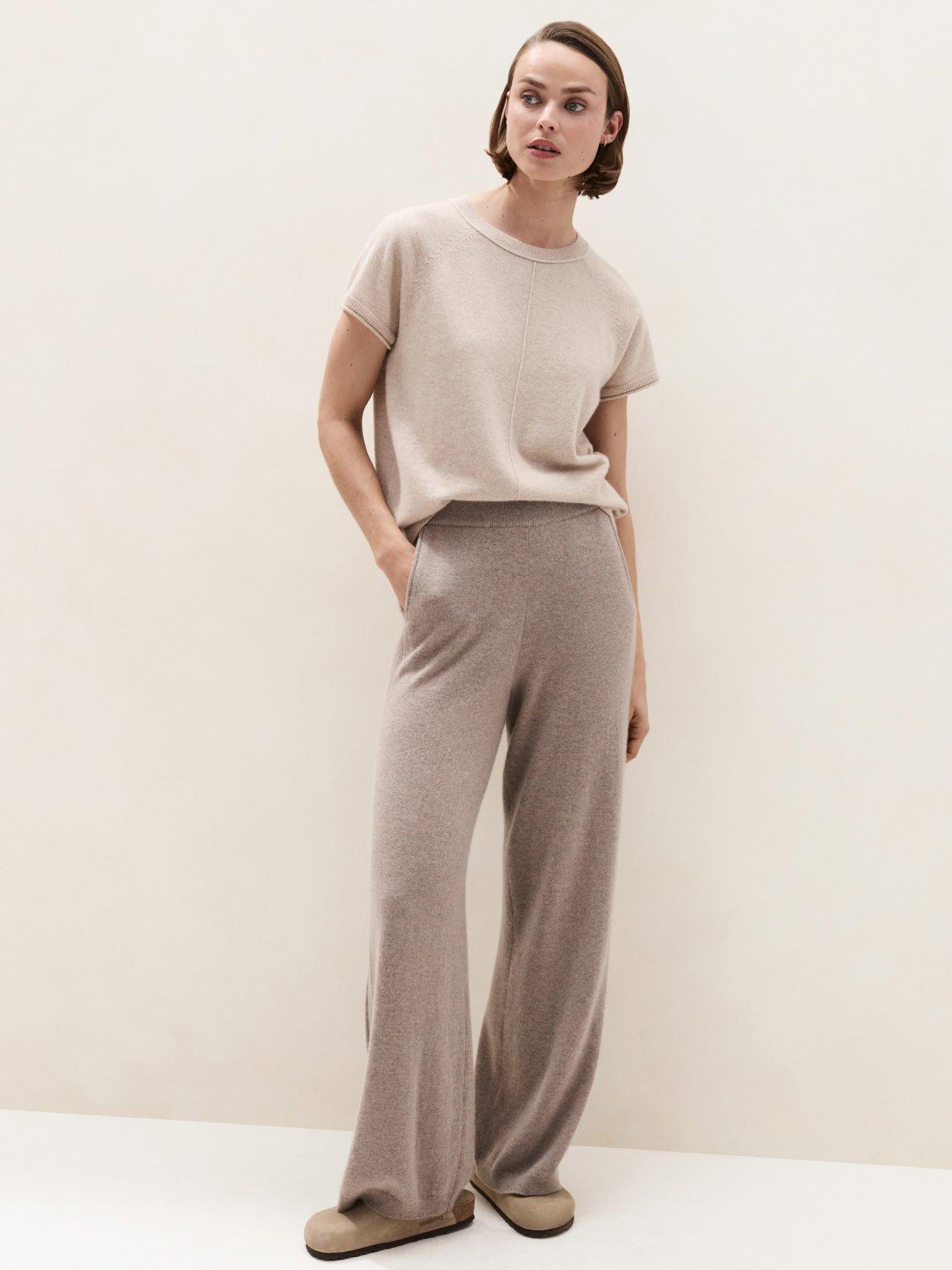 a woman in a beige t - shirt and grey pants