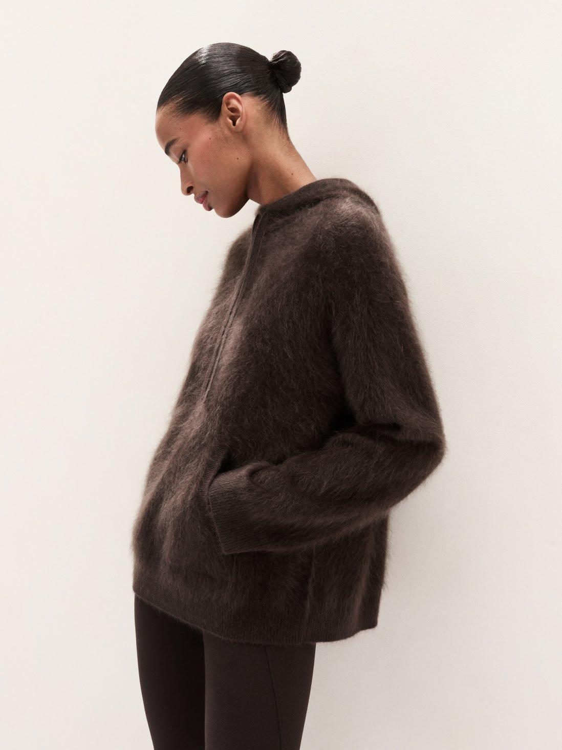 a woman in a brown sweater and black leggings