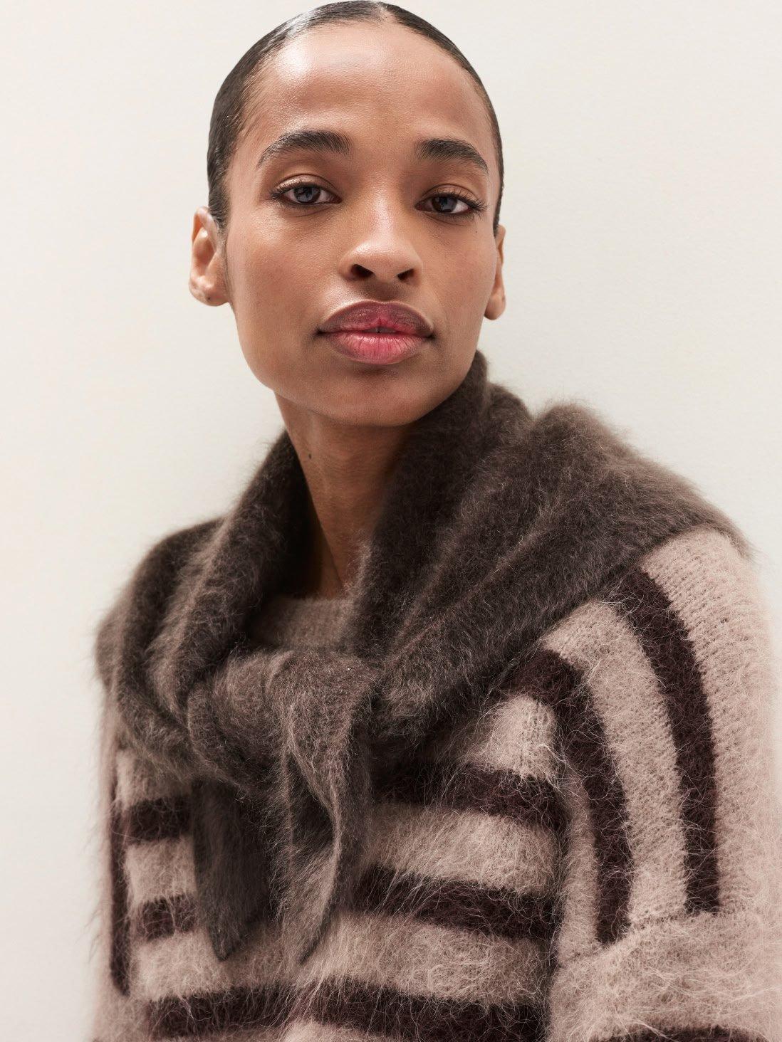 a woman with a sweater on and a black and white striped shirt