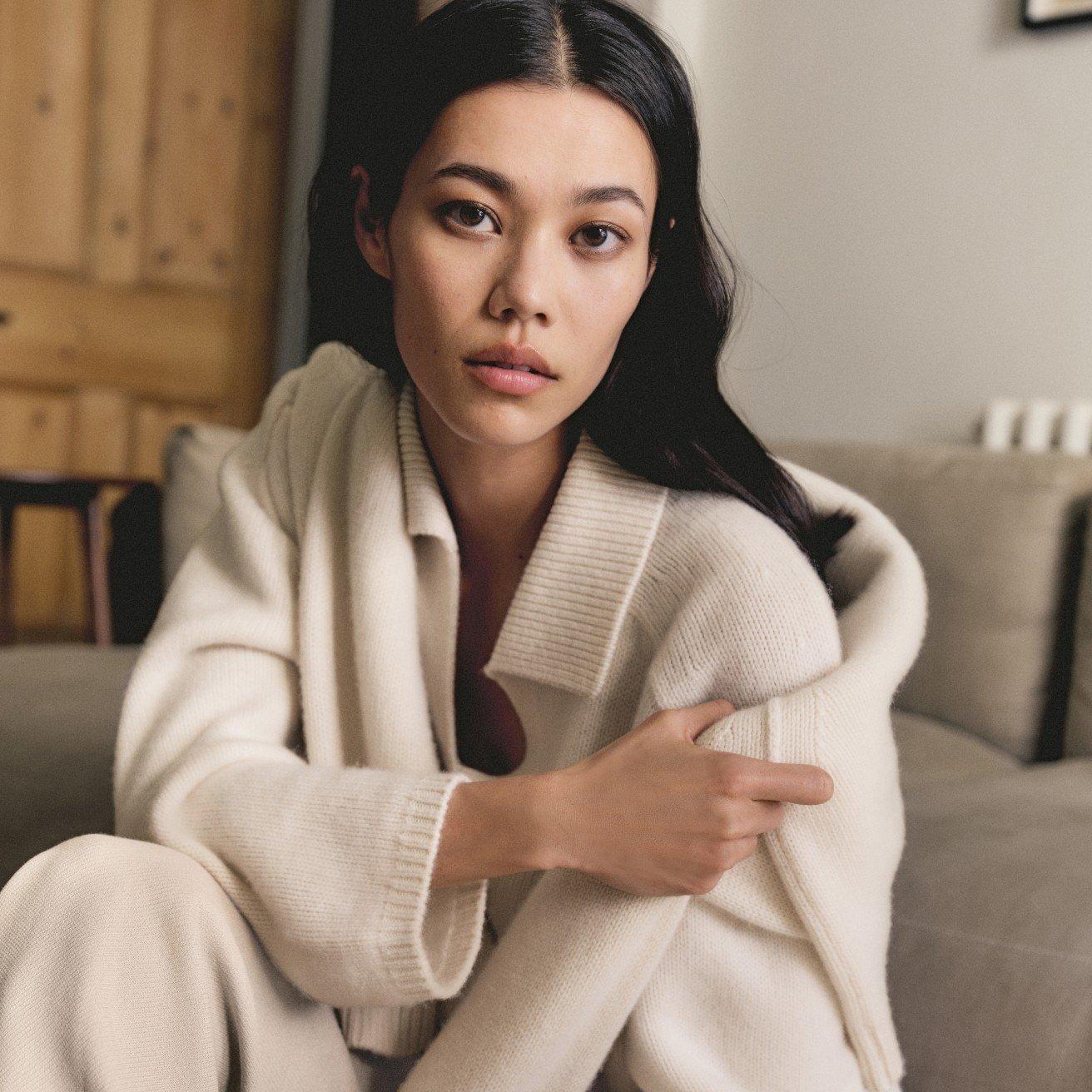 a woman in a white sweater sitting on a couch