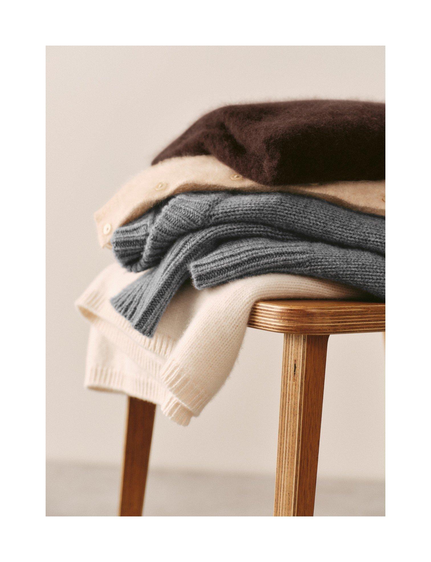 a stack of sweaters on a chair with a yellow ball