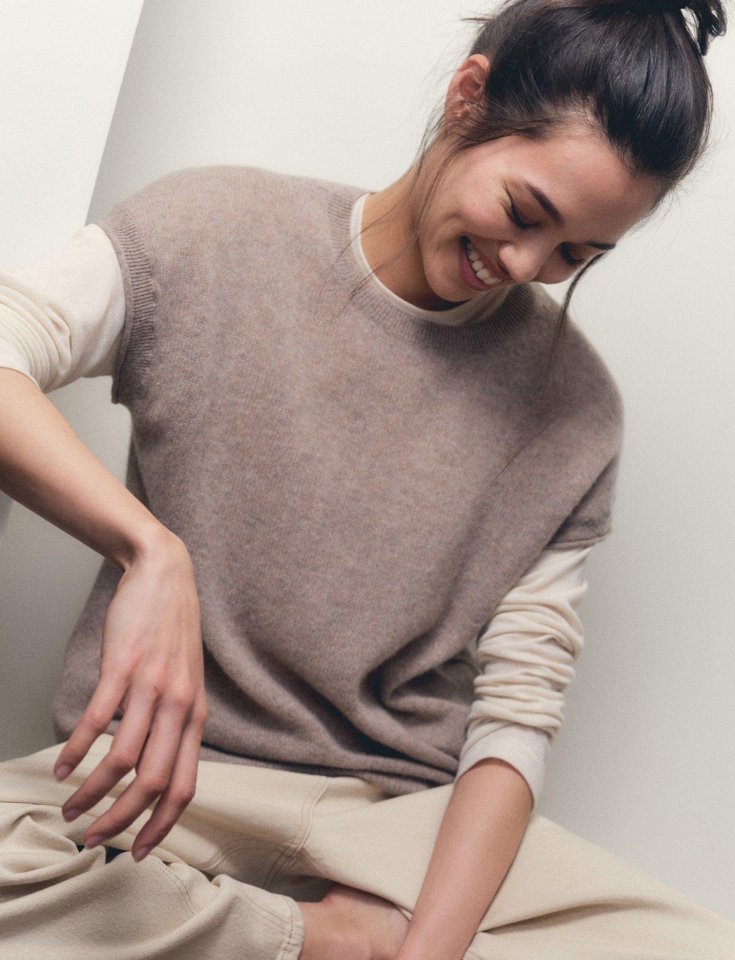 a woman sitting down wearing a cashmere jumper
