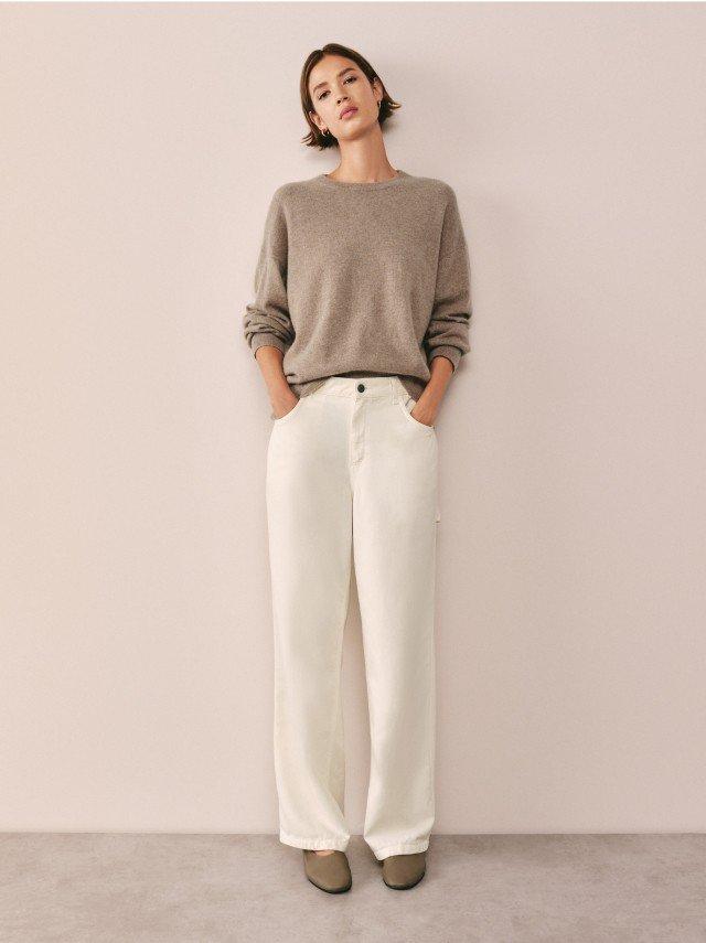 a woman in a grey sweater and white pants