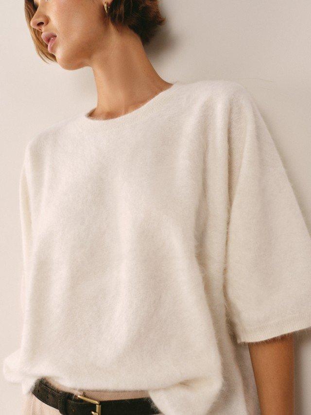 a woman wearing a white sweater with a yellow circle on it