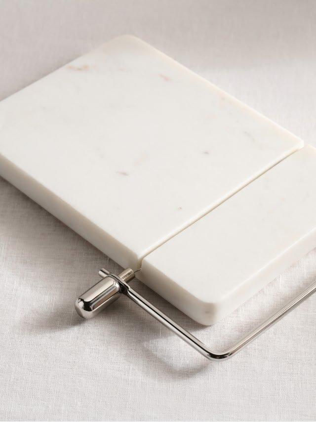 a white marble cutting board with a metal handle on a white cloth