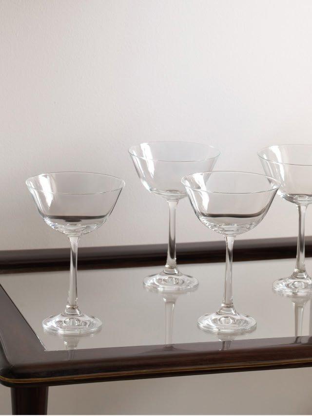 a tray with four empty wine glasses on it sitting on a table