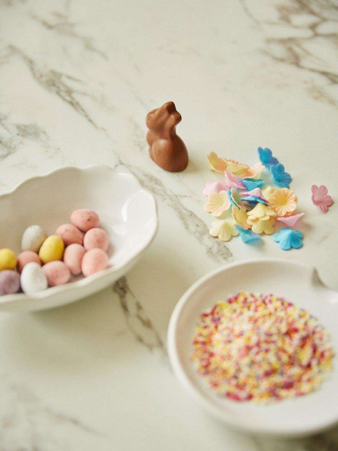 a white table with a bowl of sprinkles and a bowl of candy