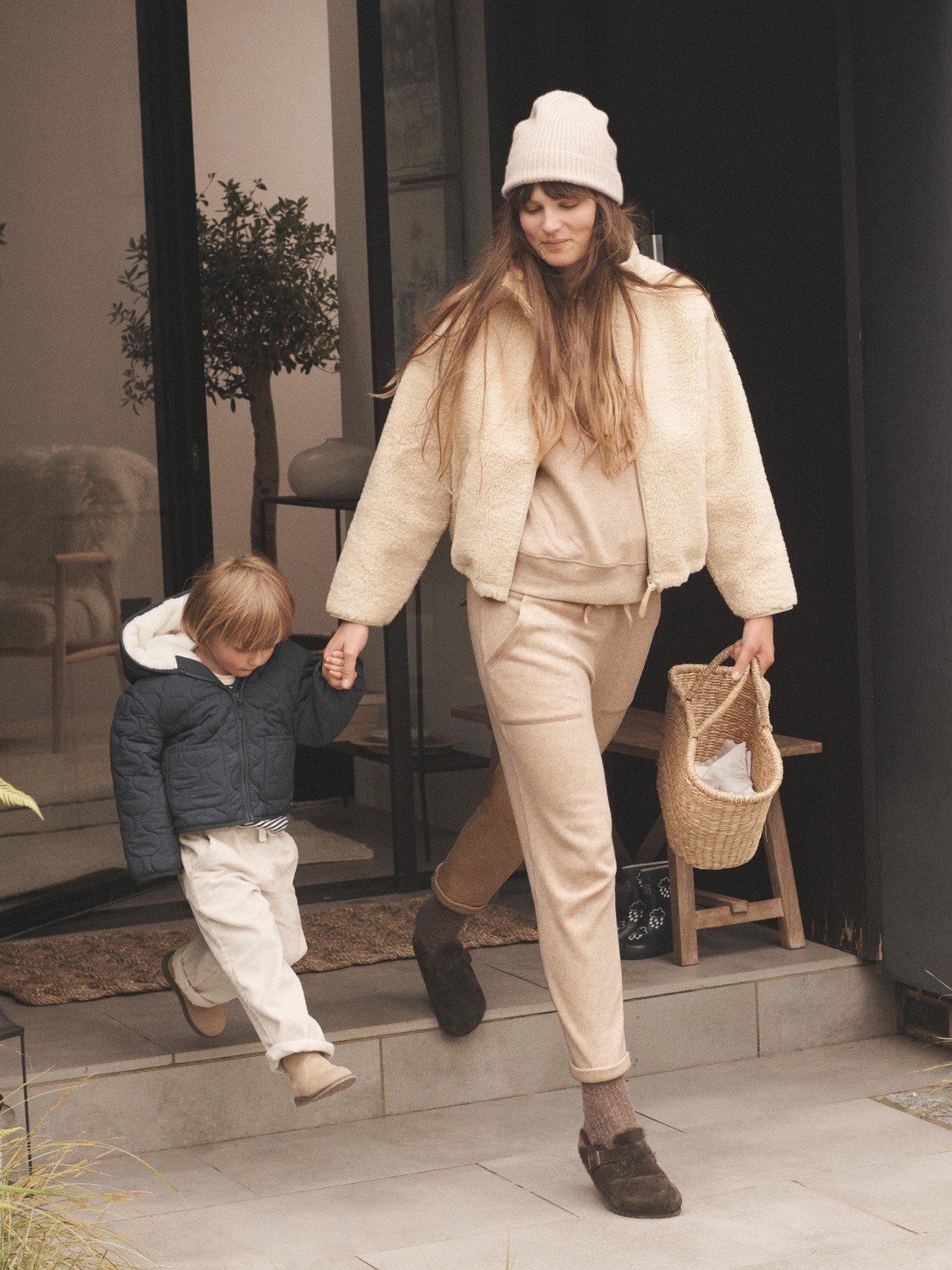 a woman and child walking out of a house with a basket