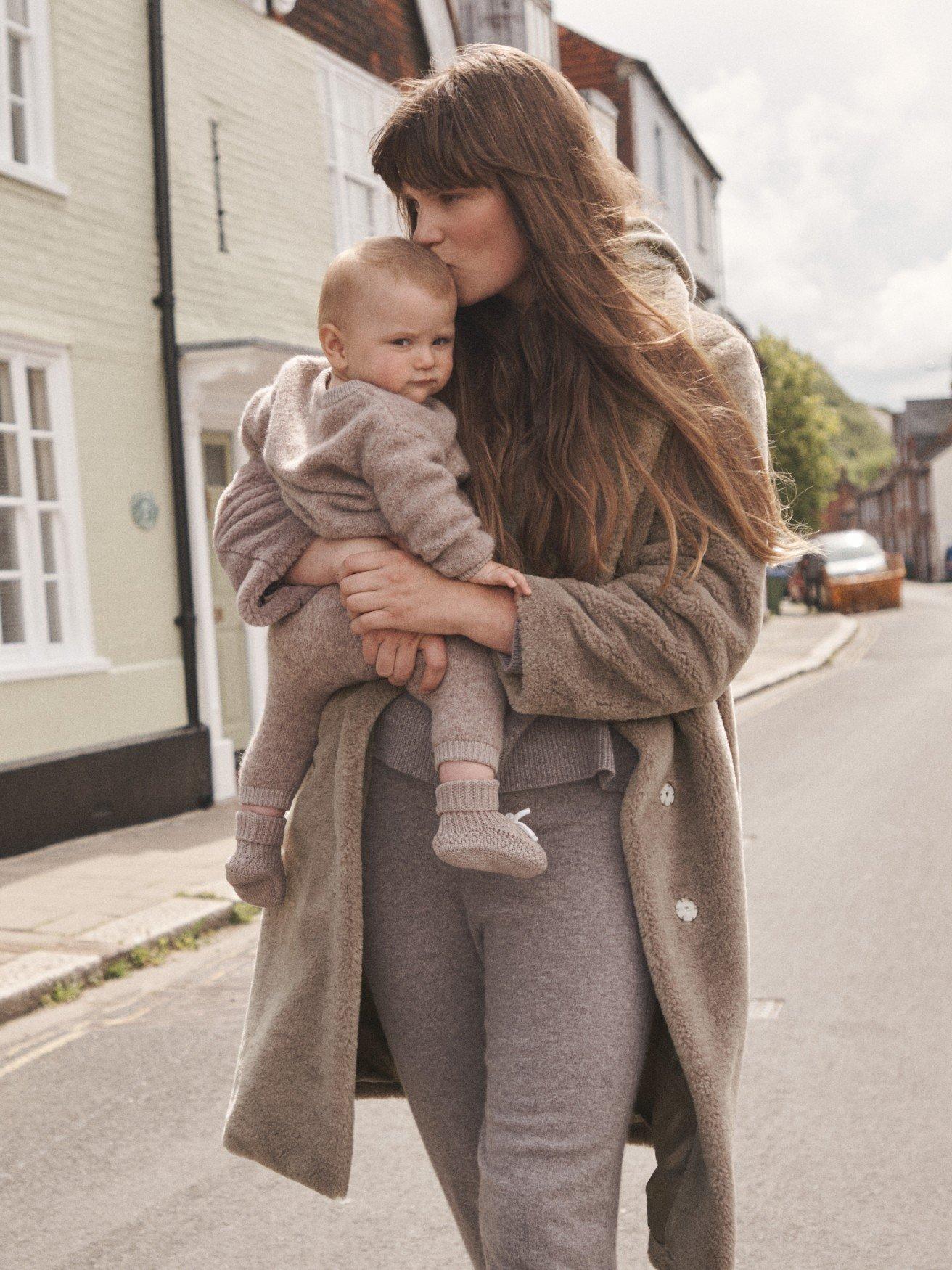 a woman walking down the street with a baby in her arms