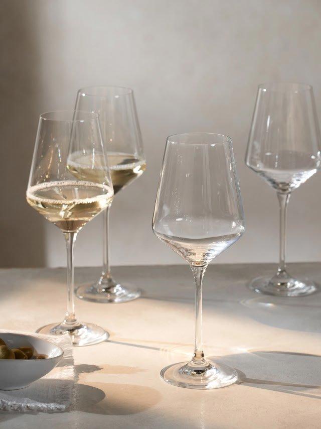 a group of wine glasses on a table with a bowl of grapes