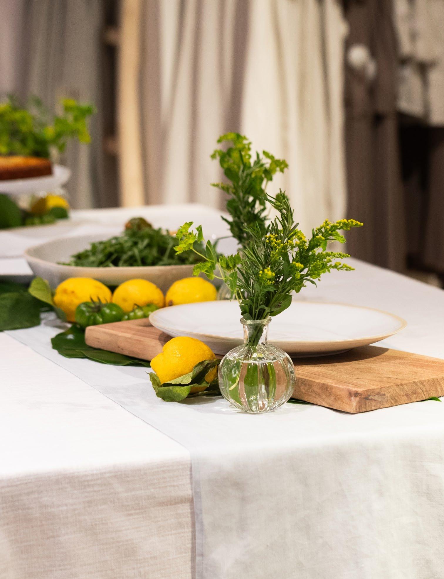 a table with a vase of lemons and a plate of food