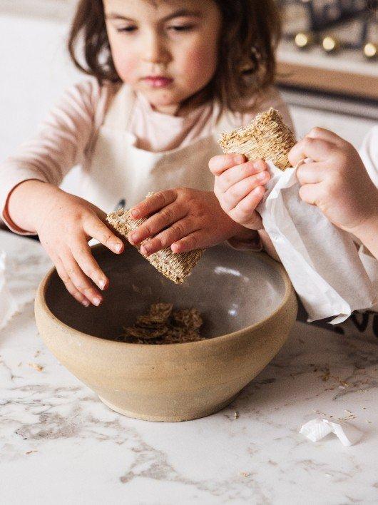 two children are making a chocolate cake on a table