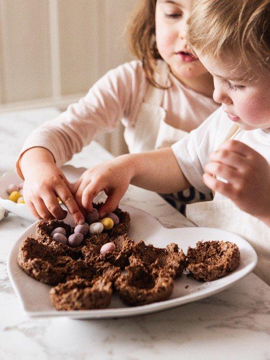 a little girl laying on a table next to a tray of cupcakes
