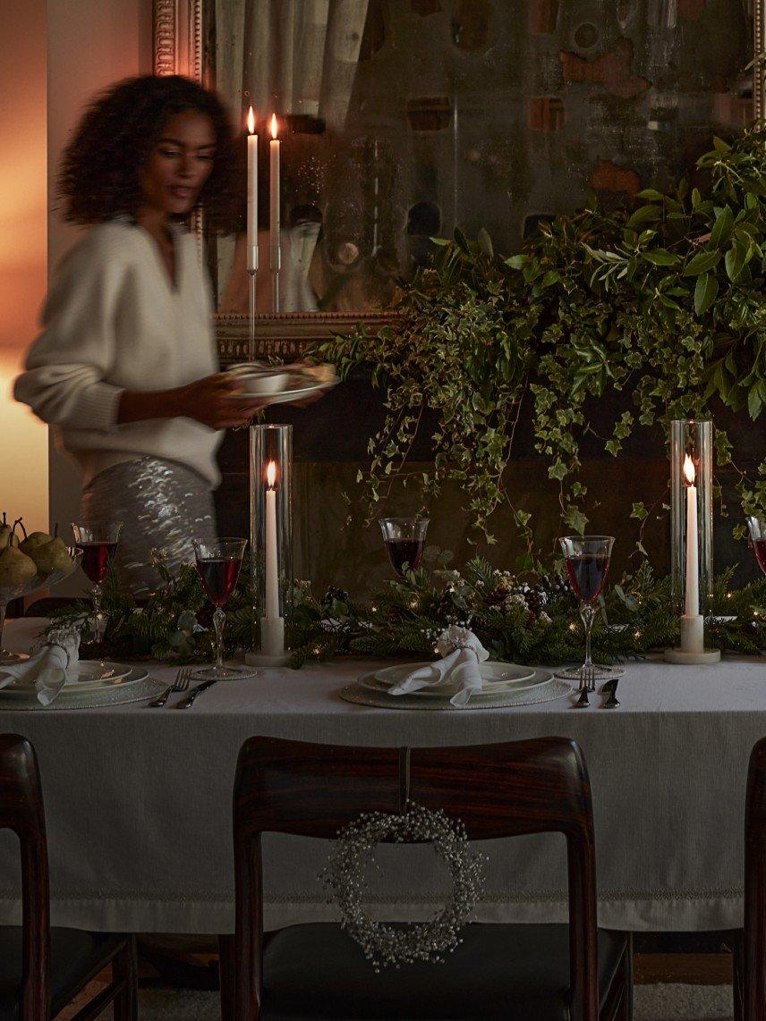 a woman standing in a dining room with a table set for a meal