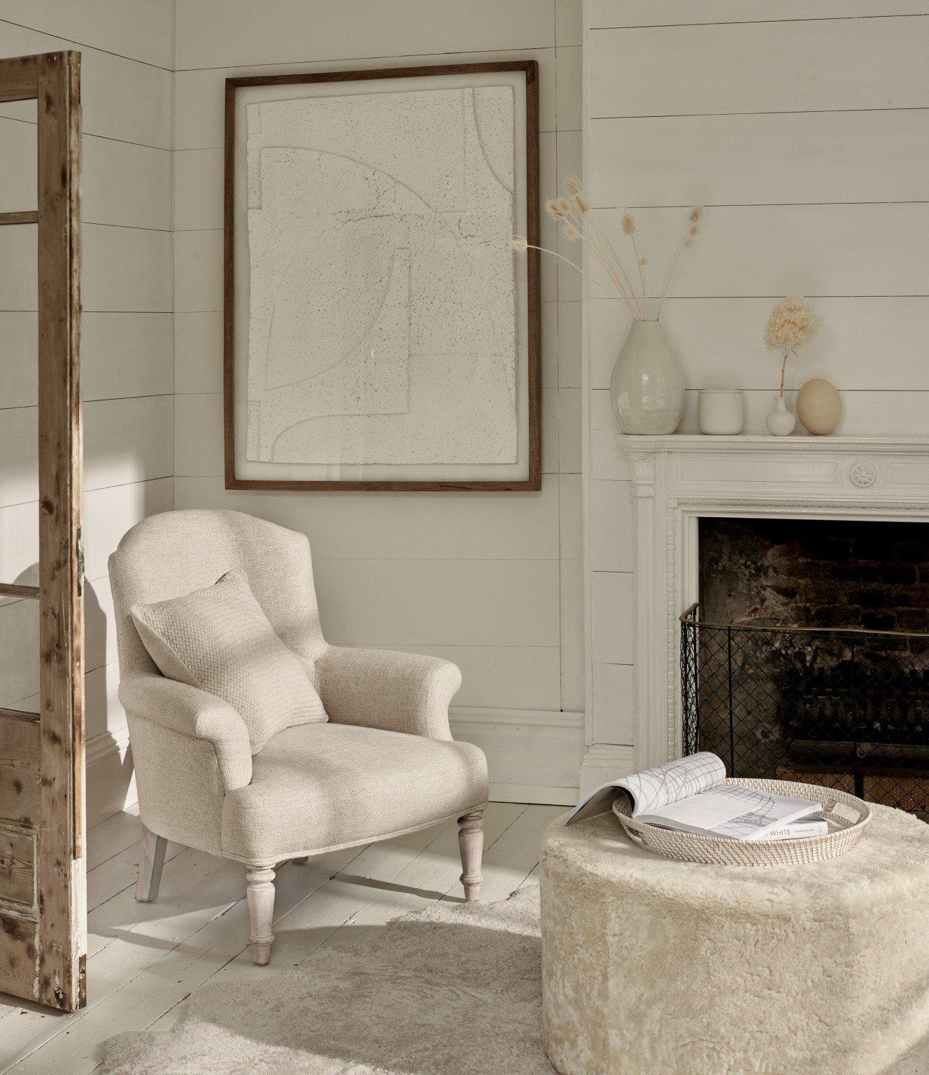 a living room with a fireplace and a chair and ottoman