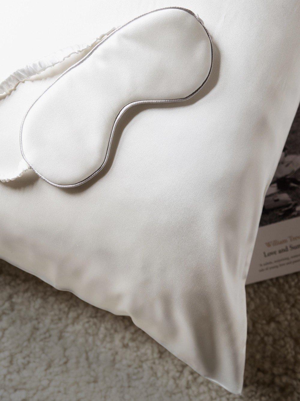 a white pillow with a white eye mask on it sitting on a bed