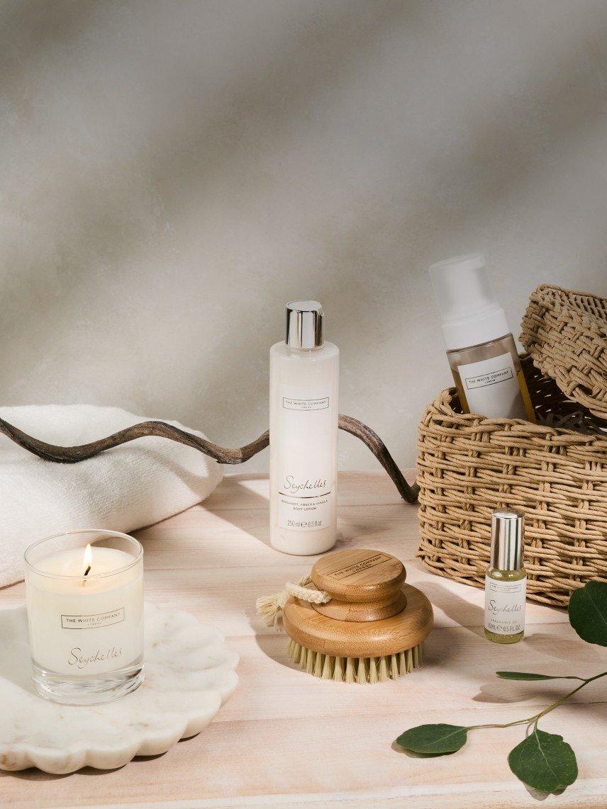 a wooden table with a basket and a candle and a bottle of lotion