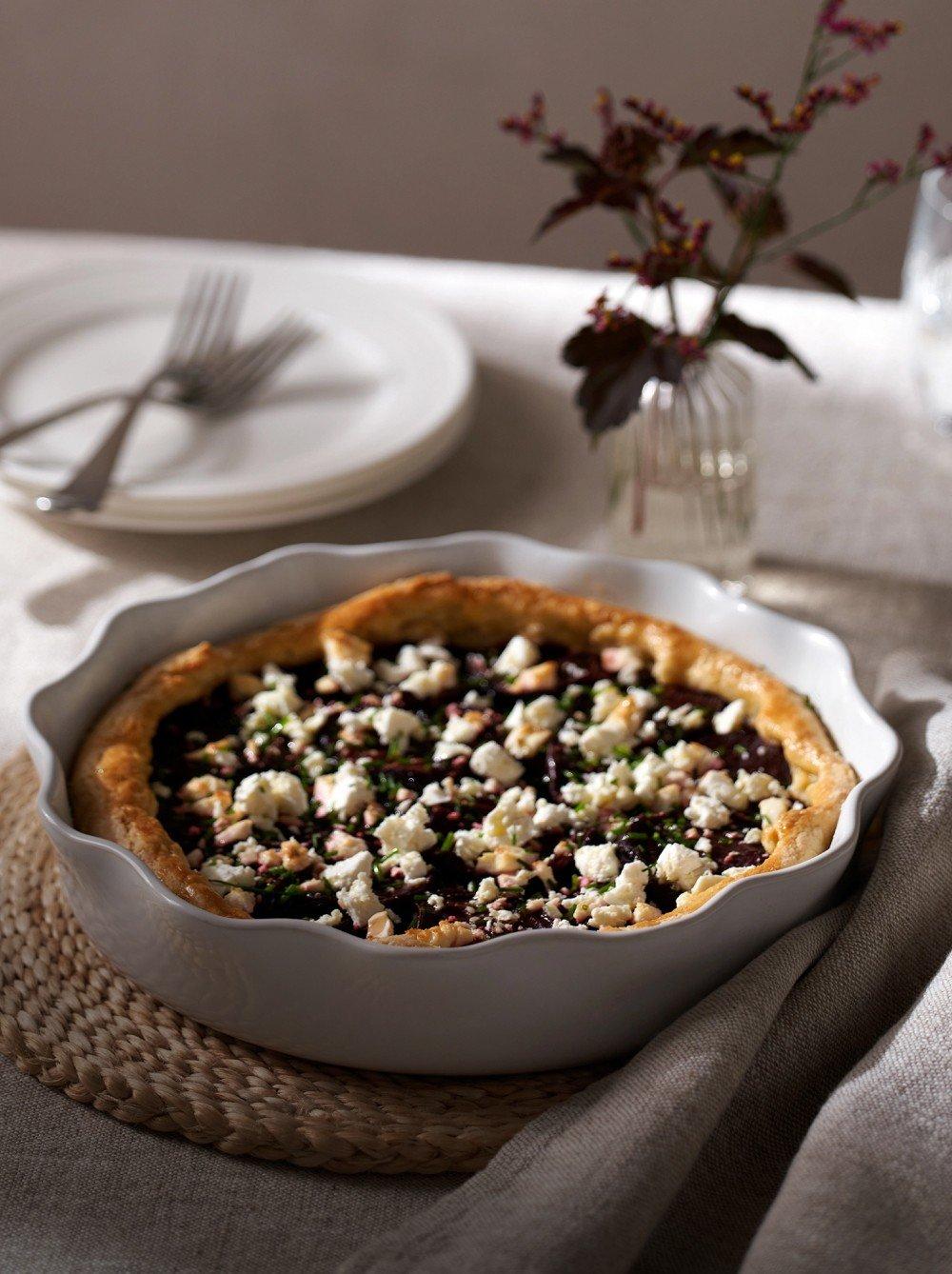 a white pie with blueberries and cheese on a white plate