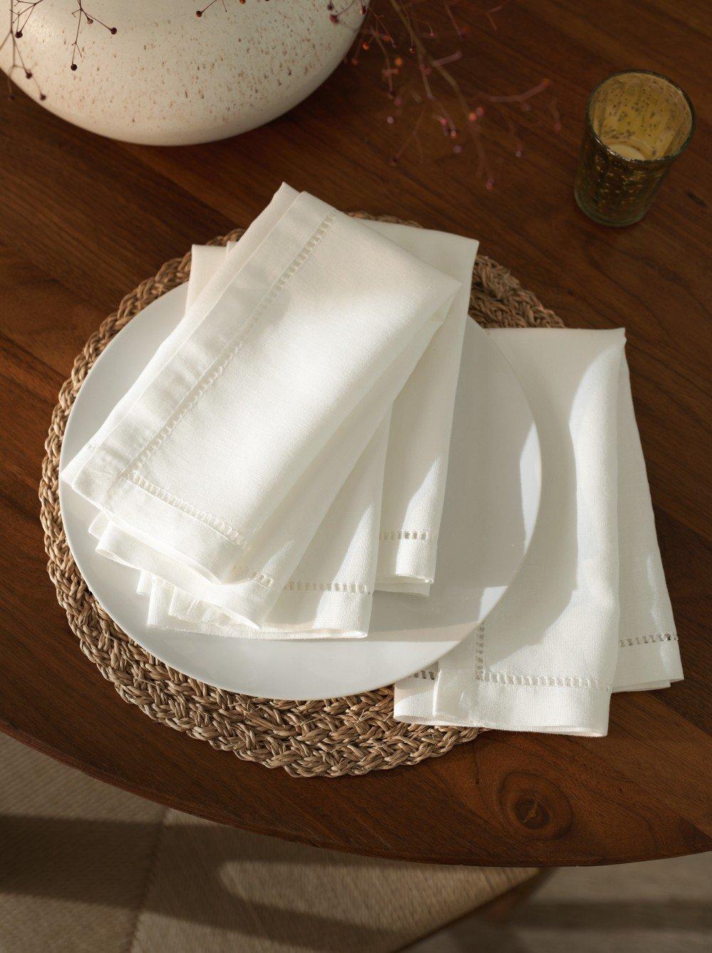 a white napkins on a plate on a table next to a vase