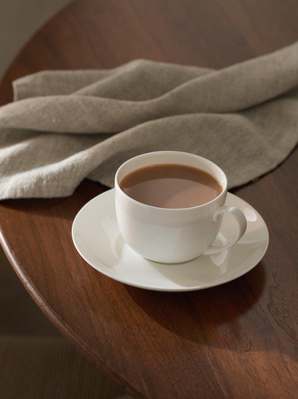 a cup of coffee on a wooden table with a napkin