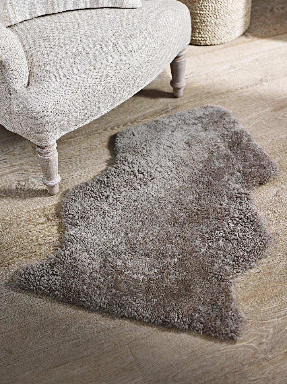 a grey rug on a wooden floor next to a chair