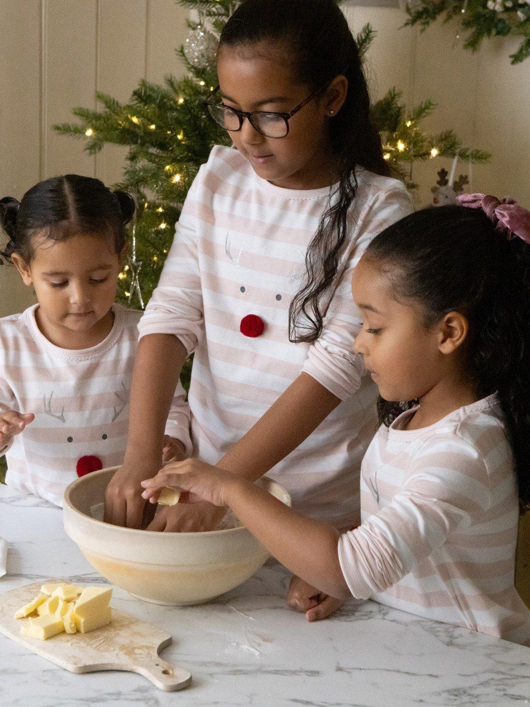 three girls are making a christmas cookie dough together