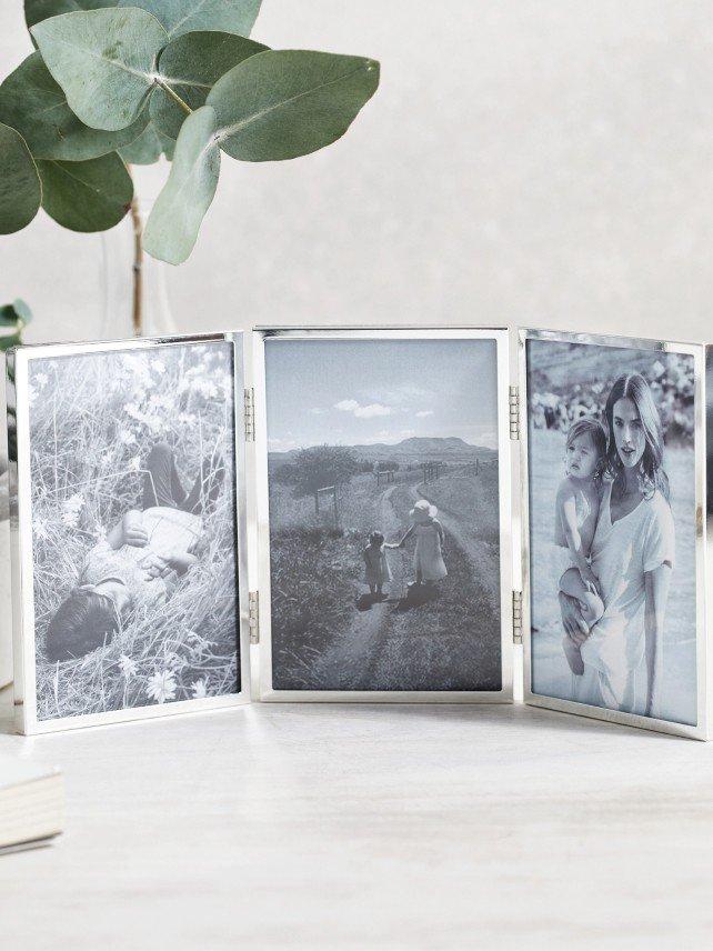 three photo frames sitting on a table next to a plant