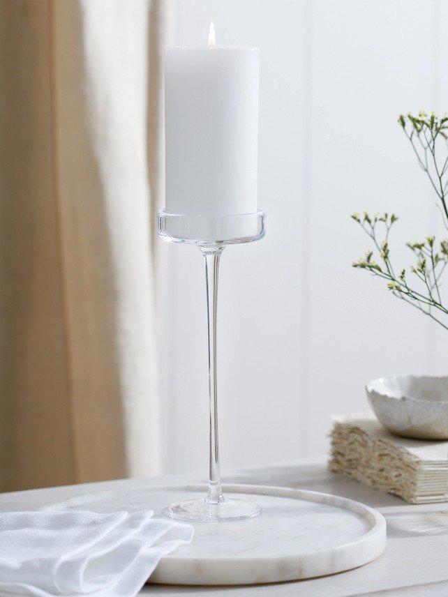 a white candle on a tray with a white vase on it