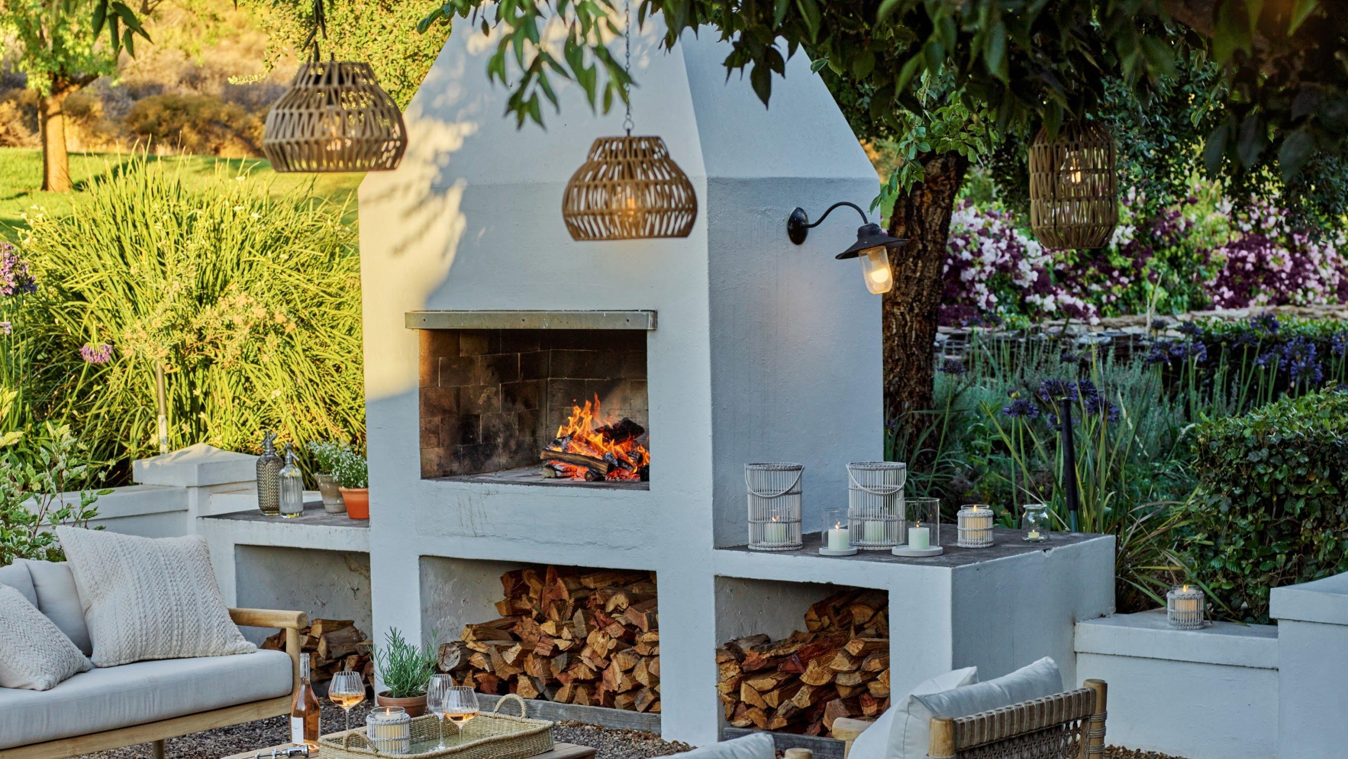 a white fireplace in a garden with a table and chairs 