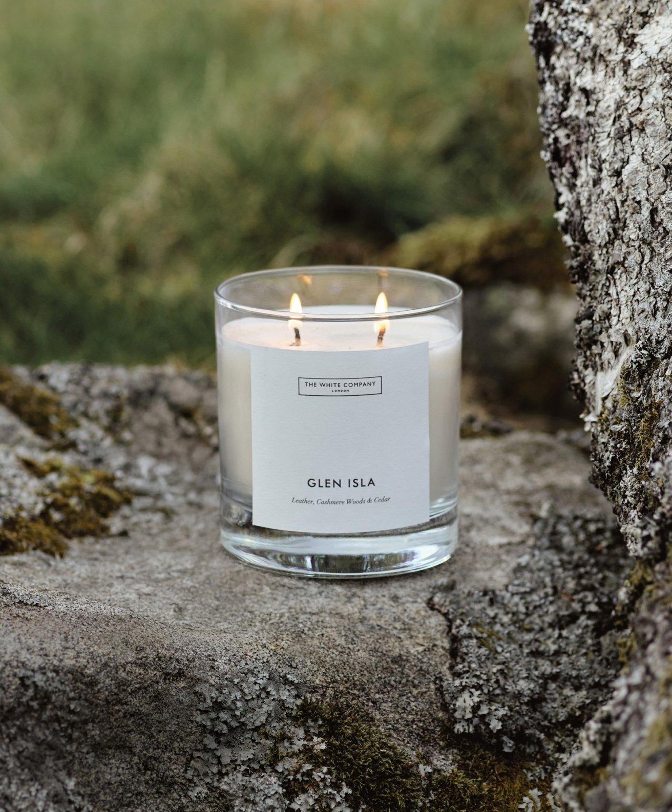 a candle sitting on a rock in the middle of a forest